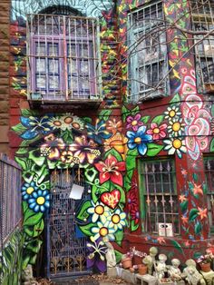 a colorful building with lots of flowers painted on it's side and an iron gate