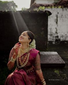 a woman sitting on top of a wooden bench wearing a red and gold sari