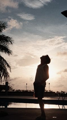 a person standing in front of a body of water with the sun setting behind them