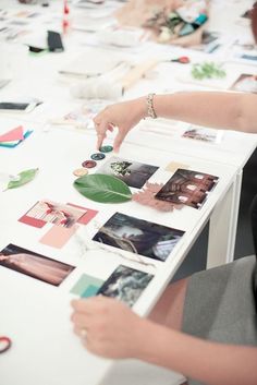 a table with many pictures on it and a person reaching for something in the middle