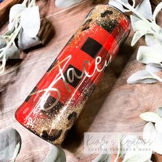 a can of soda sitting on top of a wooden table next to some leaves and flowers