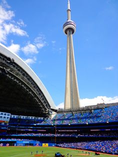 a baseball stadium with a tall tower in the background and people playing on the field