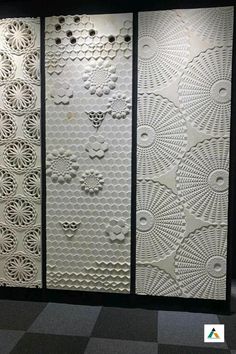 three panels with intricate designs on them in an office building, one is white and the other is black