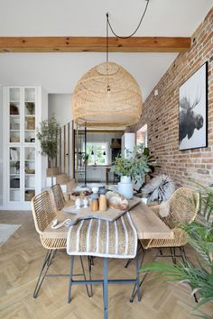 a dining room table and chairs in front of a brick wall with potted plants