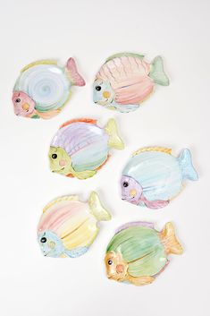 five ceramic fish on a white surface, each painted with different colors and sizes to match