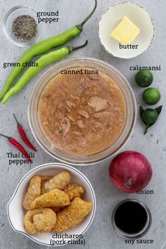 ingredients to make an enchilada recipe laid out on a gray surface with green peppers, limes, and butter