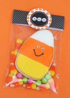 an orange and white candy bag with a happy face on it, surrounded by candies