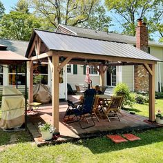 a covered patio with chairs and an umbrella on the deck in front of a house