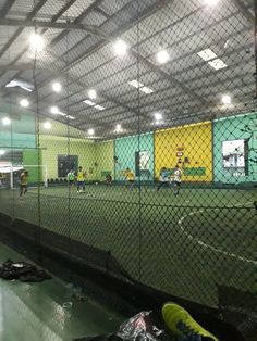 the inside of an indoor batting cage with people playing baseball on it and in the background