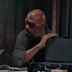 a man sitting at a table with a briefcase in front of him and his hand on the suitcase