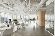 an office with white chairs, tables and people in the room looking out on the city