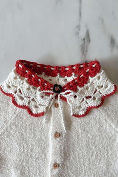 a white shirt with red and white crocheted collar on a marble countertop