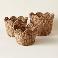 three woven baskets sitting side by side on a white surface