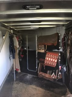 the inside of a horse trailer filled with saddles and other things in storage area