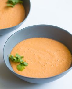 two blue bowls filled with soup and garnished with cilantro on top