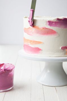 a white cake with pink icing and a knife stuck in it