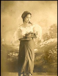 an old photo of a woman with flowers in her hands, standing on a sidewalk