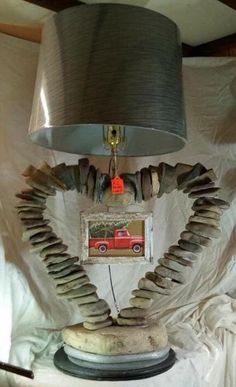 a lamp that is sitting on top of a white cloth covered bed with a red truck underneath it