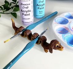 two plastic dachshunds sitting on top of a table next to some paint