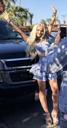 the woman is taking a selfie with her cell phone while standing in front of some cars