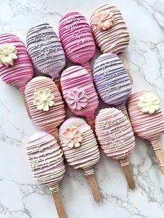 there are many pink and purple cake popss on the table with wooden skewers