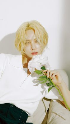 a woman with blonde hair holding a white flower