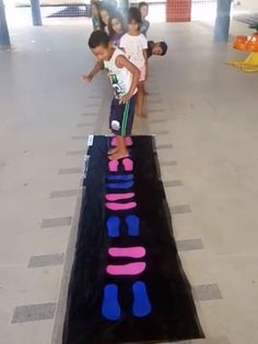 two children are standing on a large piece of art in the middle of an indoor area