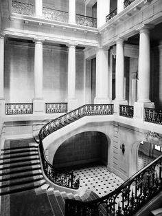 an old black and white photo of the inside of a building with stairs, balconies, and tiled floors