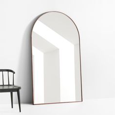 an arched mirror sitting next to a chair