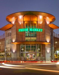 a large building with a sign that says fresh market on it's front at night