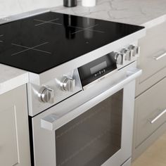 a stove top oven sitting inside of a kitchen next to white cabinets and counter tops