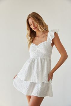 Get ready for sunny days in the Ashlyn Sweetheart Ruffle Fit and Flare Mini Dress! This white mini dress features a feminine sweetheart neckline, delicate flutter sleeves, and a flattering fit and flare silhouette. Unique with a floral texture and double tiered skirt, this white babydoll dress is ready to bloom! Accessorize to complete the look!Details 100% Polyester Elastic straps Smocked back panel Partially lined Hand wash cold/ hang dry Cute Floral Dresses White, Cheap Fitted Mini Dress With Smocked Bodice, Cheap Casual Mini Dress With Sweetheart Neckline, Cheap Flirty Mini Dress With Sweetheart Neckline, Stevie Sweetheart Mini Dress, Grad Picture Outfits High Schools, White Dress Church, Grad Picture Outfits, Senior Pictures Dresses