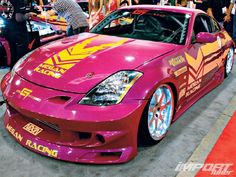 a pink sports car with yellow and red graphics on it's hood at an auto show