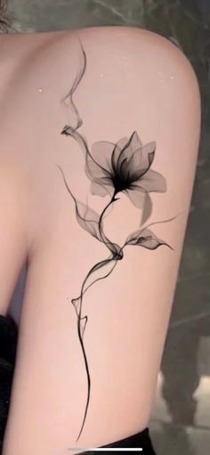 the back of a woman's shoulder with a flower tattoo on her left side