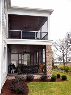 the back porch of a house with two chairs and a fan on it's balcony