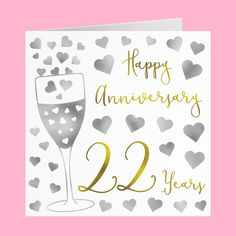 a card that says happy anniversary with hearts on it and a champagne glass in the foreground