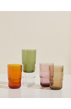 four different colored glasses sitting on top of a white table next to eachother