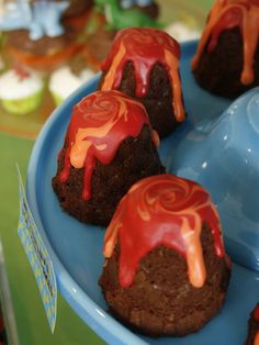 four chocolate cakes with red icing on a blue plate next to an ice cream scoop