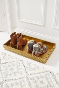 two pairs of shoes sitting on top of a gold tray next to a white door