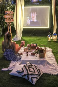 a woman sitting on the grass watching a movie