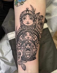 a woman's arm with tattoos on it and an image of two people in the middle