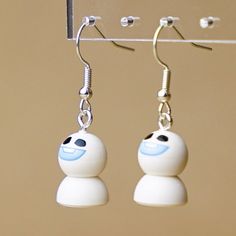 pair of white earrings with blue eyes hanging from hooks