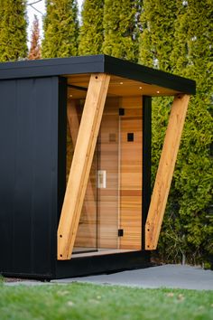 a small wooden sauna in the middle of a yard with grass and trees behind it