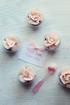 cupcakes decorated with pink frosting and topped with flowers, are arranged on a white surface