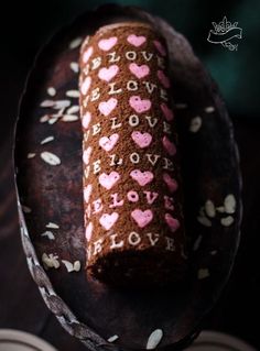 a chocolate roll decorated with pink hearts on top of a plate