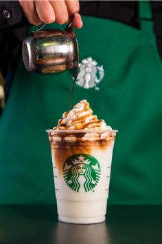 a starbucks coffee drink being poured into a cup with whipped cream and caramel on top