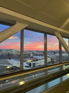 an airport terminal with planes parked at gates and windows overlooking the tarmac as the sun sets