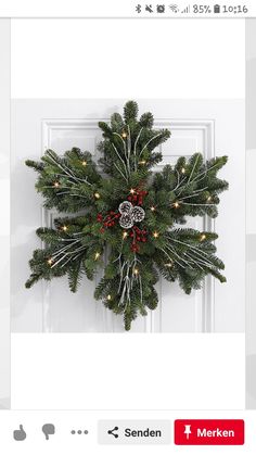 a christmas wreath is hanging on the front door with lights and snowflakes around it