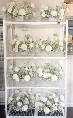 the shelves are filled with white flowers and greenery