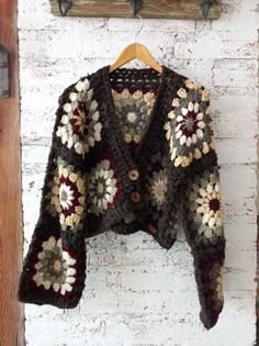 a crocheted jacket hanging on a brick wall